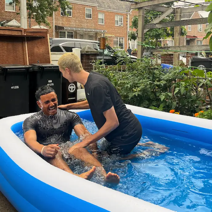 A man laughing and celebrating during a backyard baptism in an inflatable pool