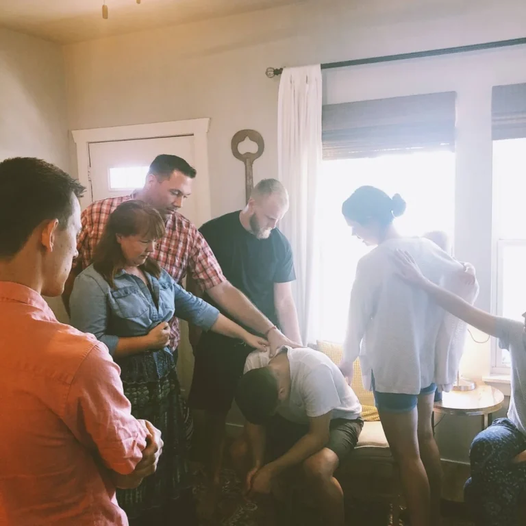 A group gathered in a home, praying over someone